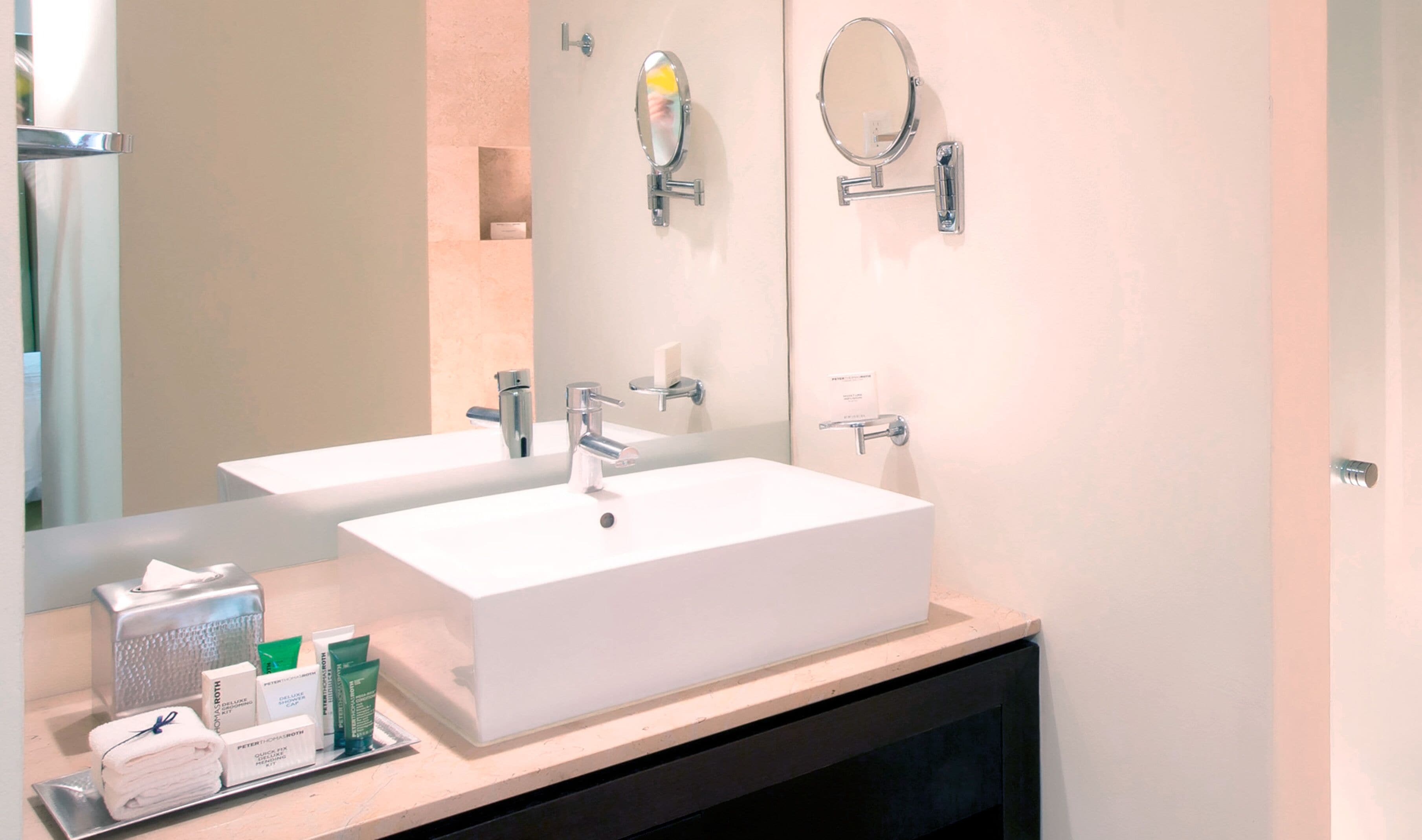 A bathroom with two sinks, a mirror, and toiletries on the counter.