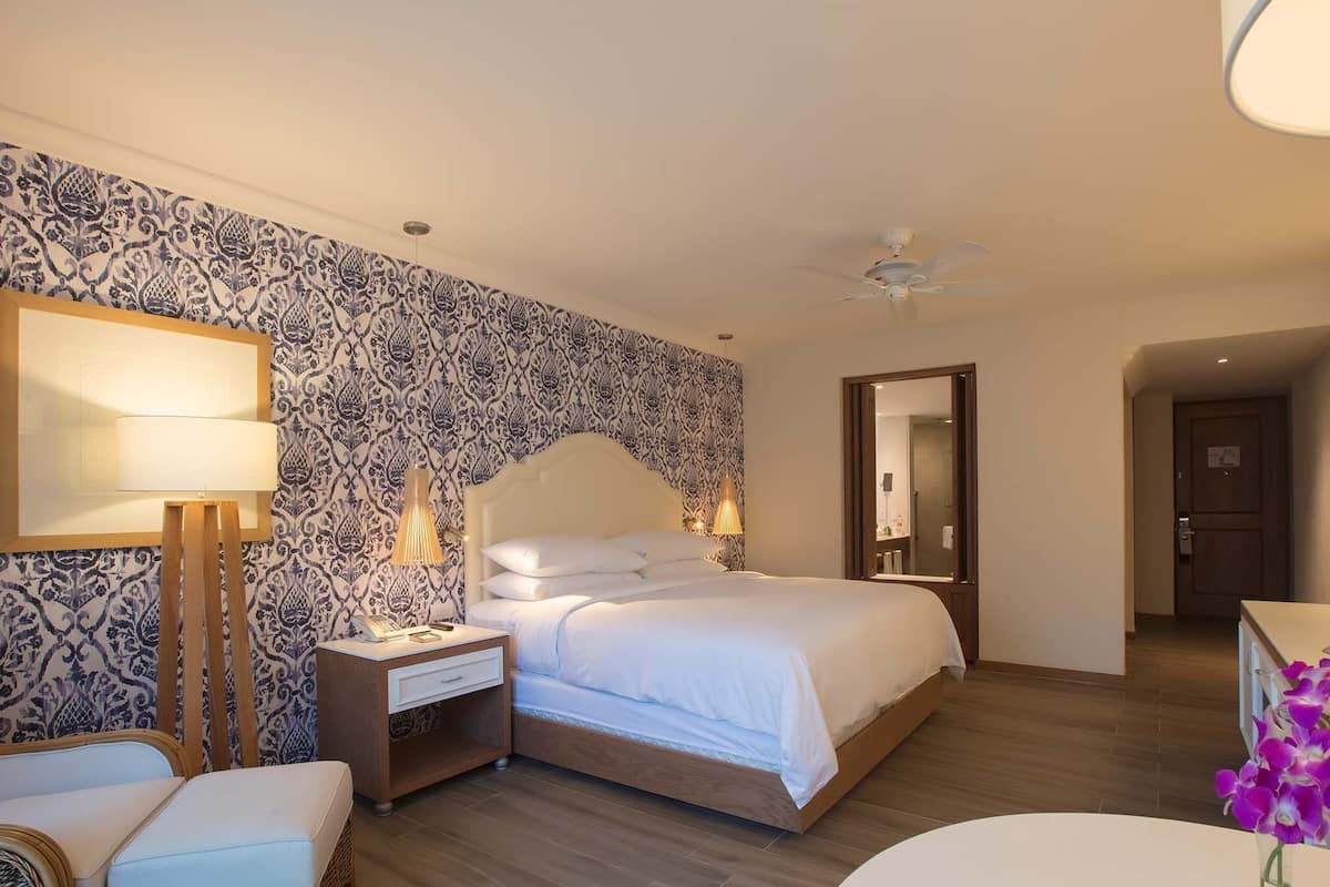 A bedroom with a bed, bedside tables, a lamp, a chair, and a mirror.