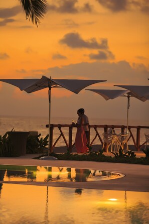 A sunset view with umbrellas and a pool reflecting the sky. - Krystal Grand Puerto Vallarta All Inclusive (Puerto Vallarta)
