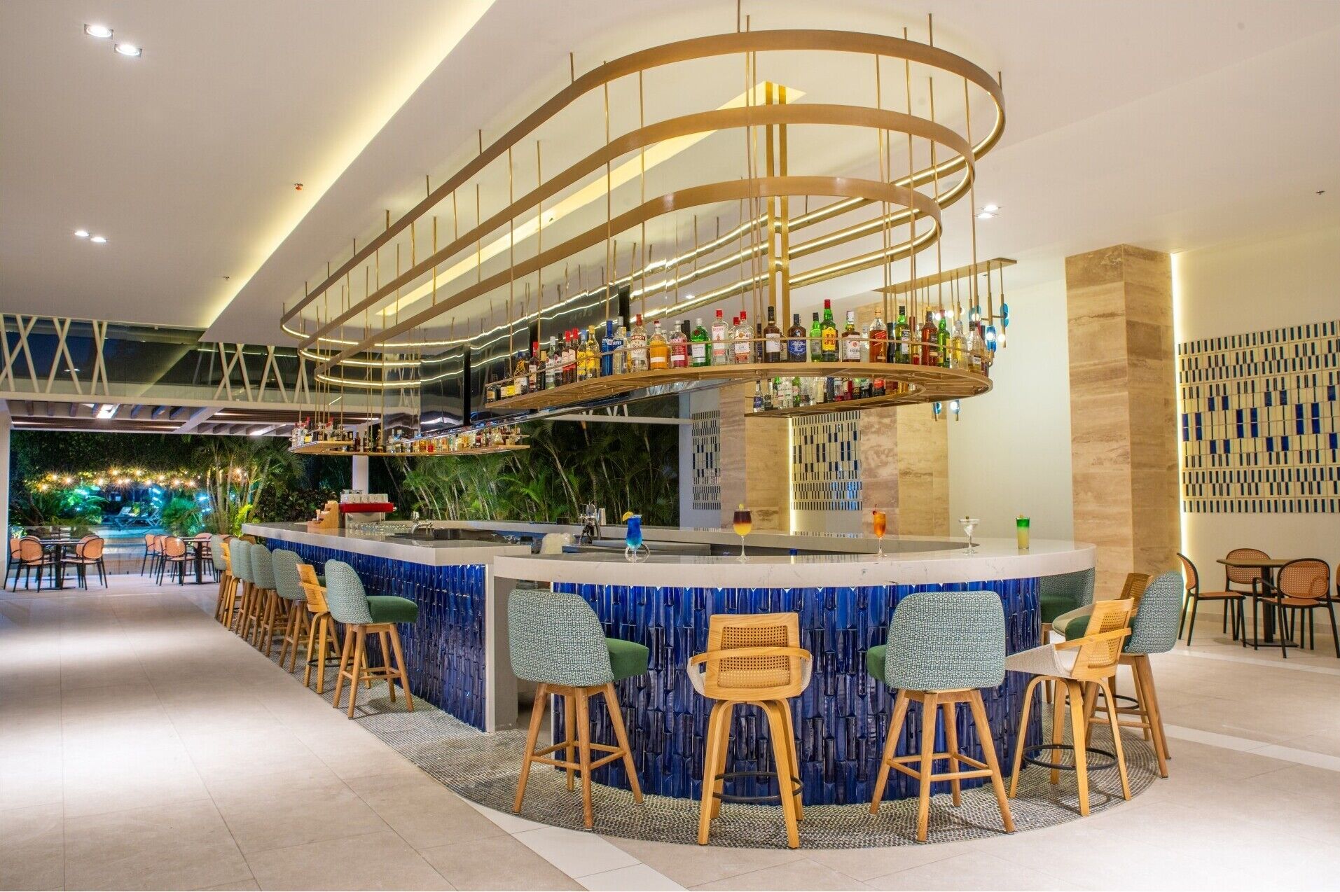 A modern bar area with a curved ceiling, multiple liquor bottles, and bar stools.
