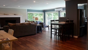 A spacious living room with a fireplace, a dining area with a table and chairs, and a kitchen area with a refrigerator. - Discover Your Perfect Getaway! Beautiful Scenic Lakefront Condo (Montague)