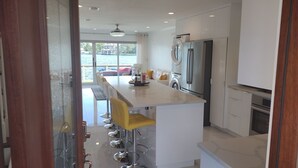 Una cocina moderna con una isla central, electrodomésticos de acero inoxidable y vistas al exterior.