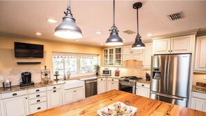 A modern kitchen with white cabinets, stainless steel appliances, and a wooden island.