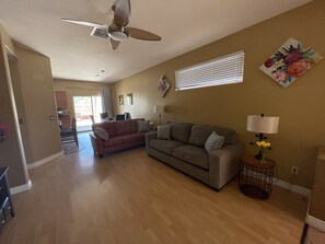 A spacious living room with a ceiling fan, a sofa, a coffee table, and a lamp.