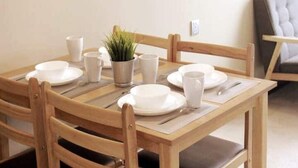 Een eettafel gedekt met witte borden, bekers en een kleine plant in een pot.