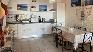 Une cuisine moderne avec des meubles blancs, un four à micro-ondes et un coin repas comprenant une table et des chaises.