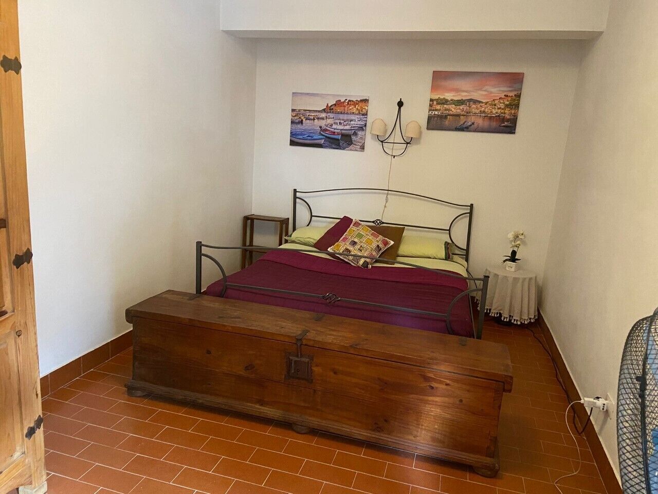 A bedroom with a bed, a chest of drawers, and two paintings on the wall.