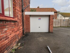 A garage with a "No Parking" sign, a brick wall, and a white garage door. - Daisy's Den (Whitby)