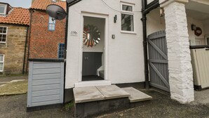 Un bâtiment blanc avec une porte, un miroir et une petite fenêtre.