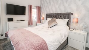 Une chambre moderne avec un grand lit, un téléviseur à écran plat, des lampes de chevet et une table de chevet.