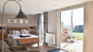 Ein Schlafzimmer mit Bett, Sofa, Heizkörper und Blick ins Freie.