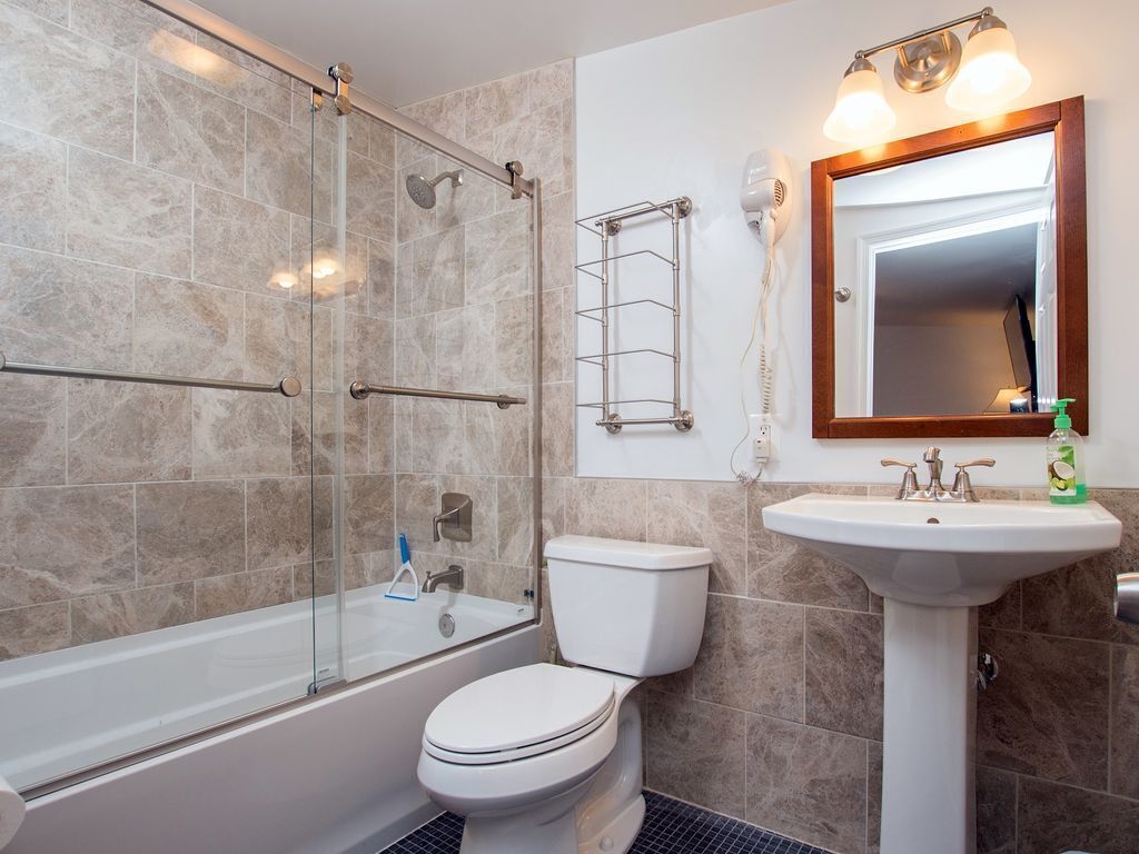 A bathroom with a glass-enclosed shower, a toilet, a sink, and a mirror.