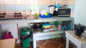 Una cocina con un lavaplatos, estufa, microondas y diversos utensilios y recipientes de cocina.