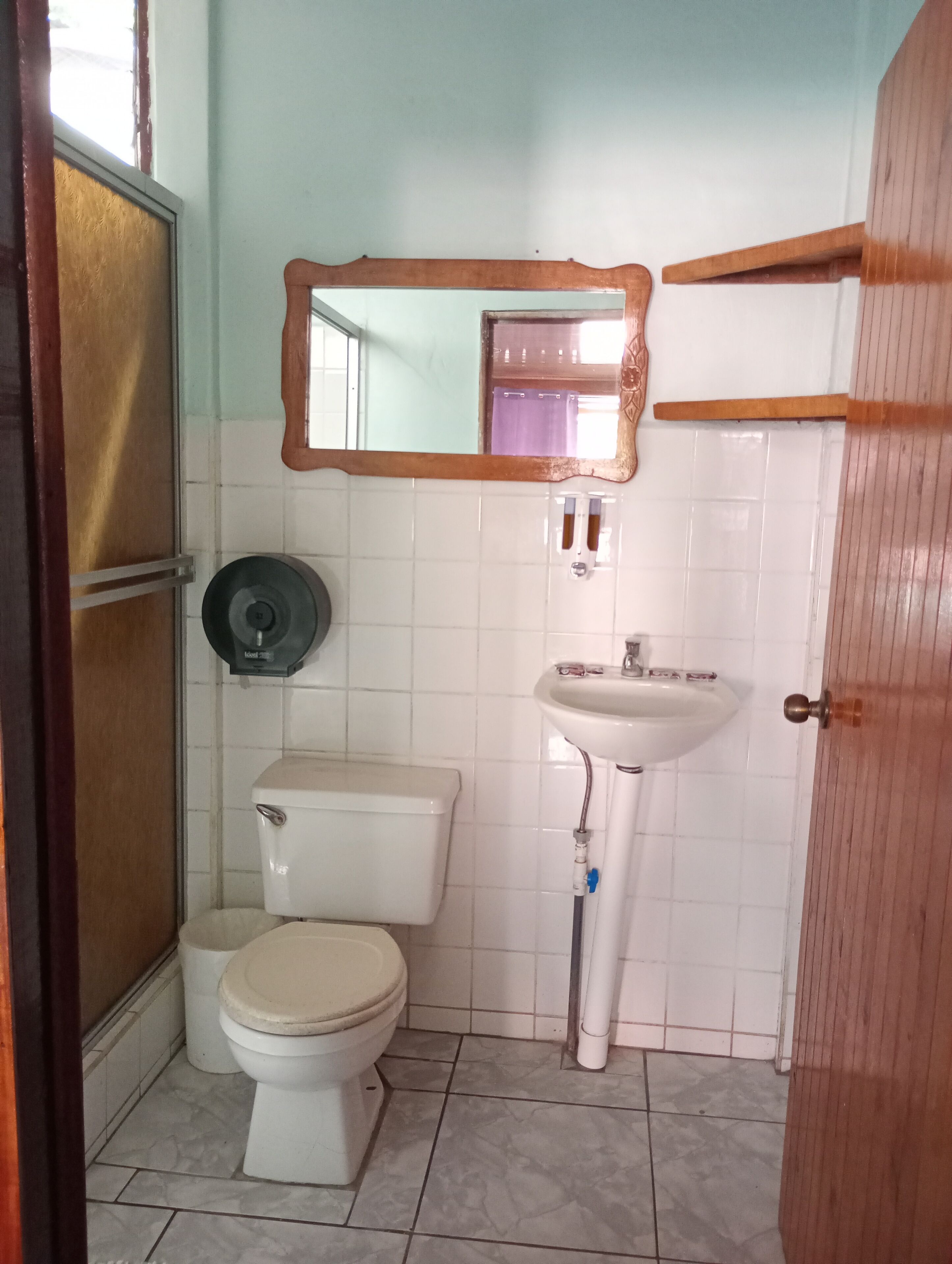 A small bathroom with a toilet, a sink, and a mirror.