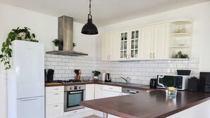 Eine moderne Küche mit weißen Schränken, einer Edelstahl-Dunstabzugshaube, einem eingebauten Backofen, einer Mikrowelle und einer großen Kochinsel mit dunkler Arbeitsplatte.