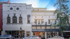 Straatbeeld van een gebouw met verschillende winkelgevels, waaronder een restaurant met terras.