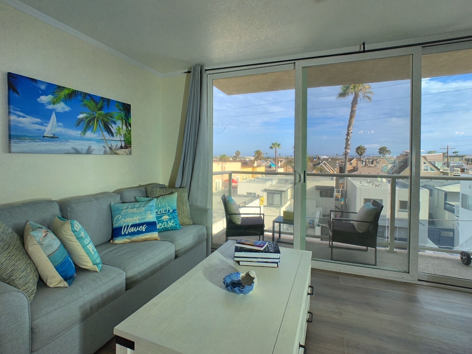 Una sala de estar con un sofá gris, una mesa de centro y un cuadro de una escena de playa.
