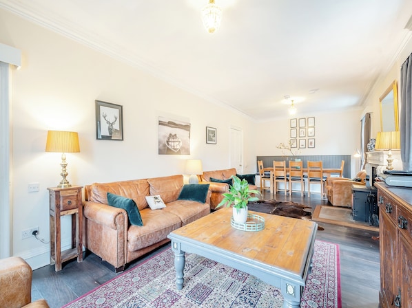 A living room with a sofa, coffee table, and a dining area with chairs and a table.