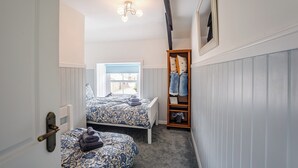 Une petite pièce avec deux lits, une fenêtre donnant sur un beau paysage, une armoire en bois et un luminaire au plafond.