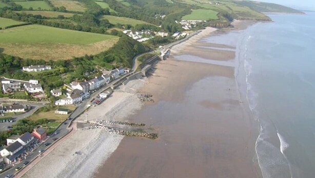 A coastal town with a sandy beach, a road running parallel to the shore, and buildings along the coastline. - Amroth Holiday home with Sea Views (Narberth)