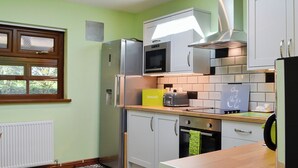 Une cuisine moderne dotée d’une verrière, d’appareils électroménagers en acier inoxydable et d’une planche à découper jaune.