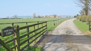 A rural road leading to Snow Hall Farm with a wooden fence and a metal gate.
