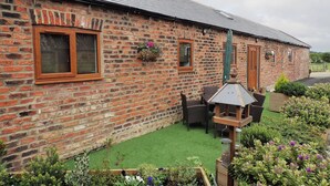 A brick building with a tiled roof, a wooden door, and a window with a flower box.