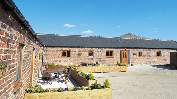 A brick building with a courtyard, outdoor seating, and a mountain in the background.