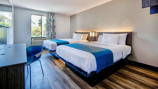 Een hotelkamer met twee bedden, een bureau en een stoel.