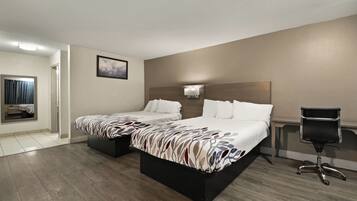 A hotel room with two beds, a desk, a chair, and a bathroom visible through an open door.
