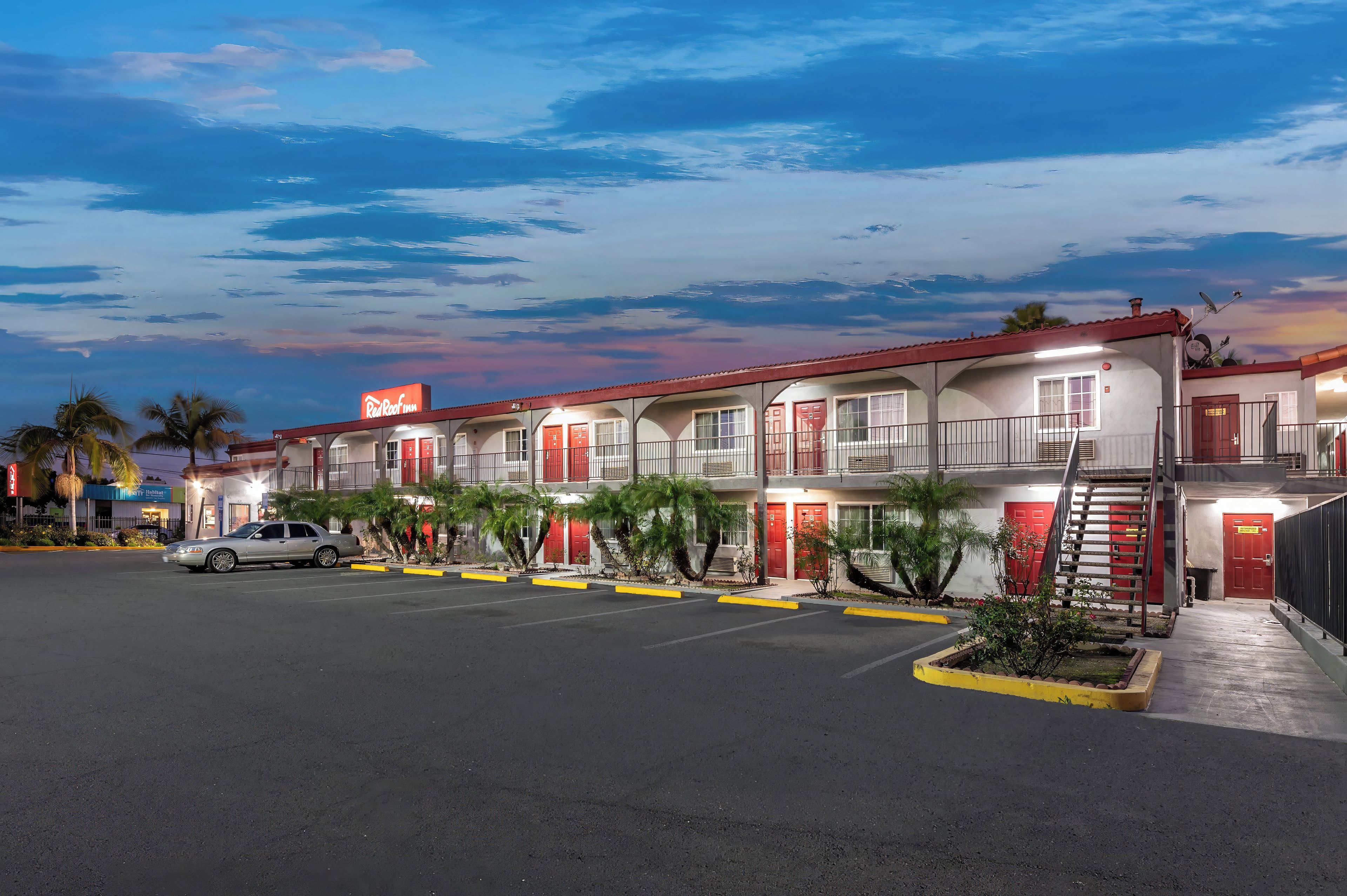 A motel with multiple units, a parking lot, and a clear sky.