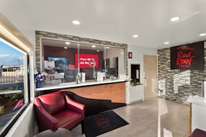 A reception area with a glass partition, a red sign offering free Wi-Fi, and a Red Roof Inn sign. - Red Roof Inn Los Angeles – Bellflower (Bellflower)