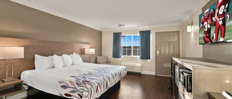 A hotel room with a large bed, bedside tables, a desk, a flat-screen TV, a window with curtains, and a view of the outdoors.