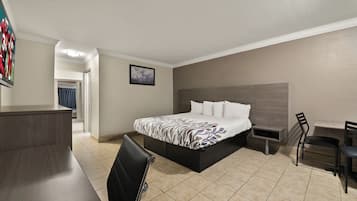 A hotel room with a bed, a desk, a chair, and a TV.
