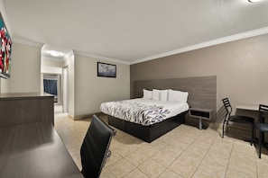 A hotel room with a bed, a desk, a chair, and a TV.
