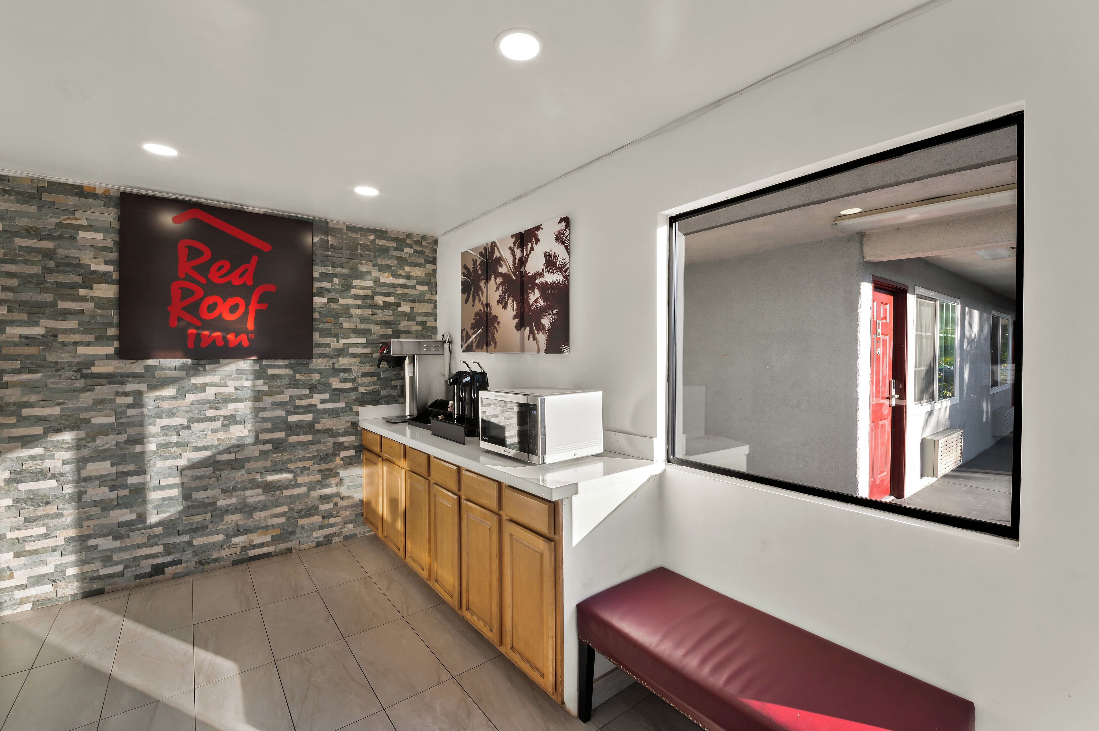 A modern kitchen with a stone backsplash, a coffee machine, a microwave, and a bench.