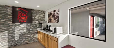 A modern kitchen with a stone backsplash, a coffee machine, a microwave, and a bench.