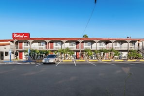 A Red Roof Inn with a parking lot and a car in front.