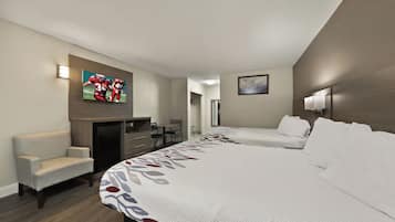 Ein Hotelzimmer mit Bett, Schreibtisch, Stuhl und einem an der Wand montierten Fernseher.