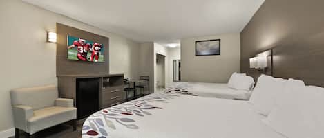 Una habitación de hotel con una cama, un escritorio, una silla y un televisor montado en la pared.