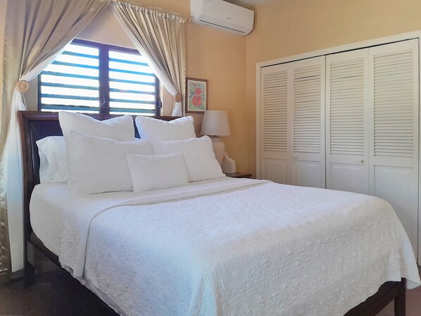 A neatly made bed with white linens, a bedside lamp, and a window with curtains. - Stylish Private Guest Suite – Comfort & Convenience await. (The Valley)
