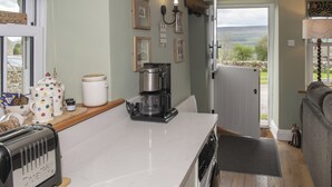 A kitchen with a coffee maker, toaster, and a view through the door.