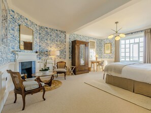 Een slaapkamer met een open haard, een bed, een bureau en een stoel.