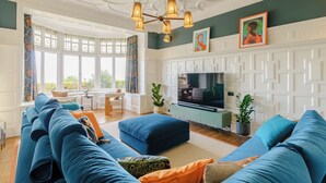Un salon avec un grand canapé bleu, un téléviseur et des panneaux décoratifs au mur.