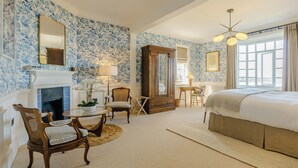 Une chambre à coucher avec une cheminée, un lit, un bureau et une chaise.