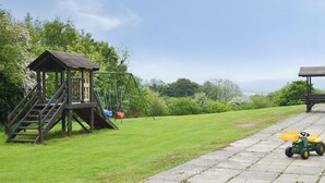 A playground with a swing set and a small wooden structure with stairs.