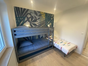 A bunk bed room with a lower bunk and a single bed. - Ker Melen single-storey wooden house 5 minutes from the beach (Finistère, Brittany) (Cléder)