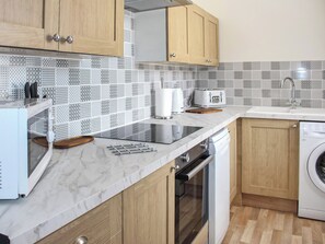 A modern kitchen with wooden cabinets, a microwave, a toaster, and a dishwasher. - Sunrise Cottage - UK35813 (Llanddulas, near Llandudno)