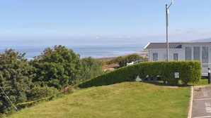 A coastal view with a white building, a street lamp, and a clear sky. - Sunrise Cottage - UK35813 (Llanddulas, near Llandudno)