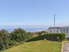 A coastal view with a white building, a street lamp, and a clear sky. - Sunrise Cottage - UK35813 (Llanddulas, near Llandudno)